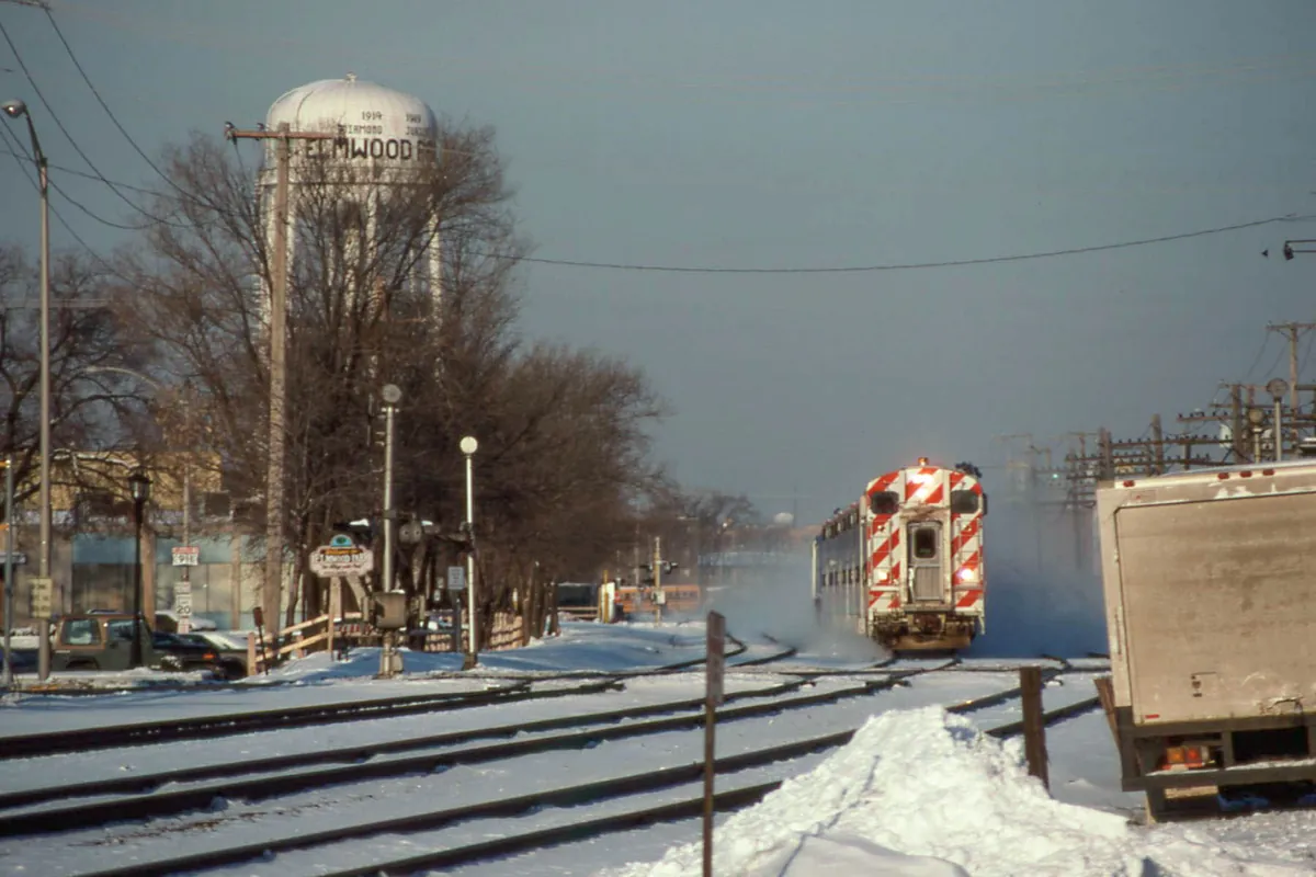 A Metra train passing the village water tower in snowy Elmwood Park, Illinois